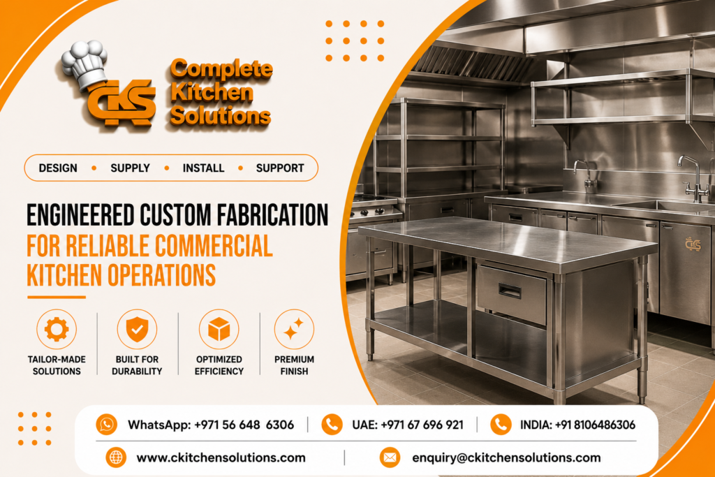 A promotional banner for "Complete Kitchen Solutions" titled "Engineered Custom Fabrication for Reliable Commercial Kitchen Operations," featuring custom-made stainless steel commercial kitchen furniture, including a central preparation table with built-in drawers, wall shelving, and integrated sink units.