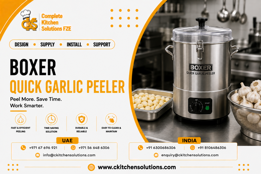 A promotional banner for "Complete Kitchen Solutions FZE" titled "Boxer Quick Garlic Peeler: Peel More. Save Time. Work Smarter," featuring an electric stainless steel Boxer quick garlic peeling machine with a transparent lid next to a stainless steel pan of peeled garlic cloves and a metal colander filled with whole garlic heads on a commercial kitchen counter.